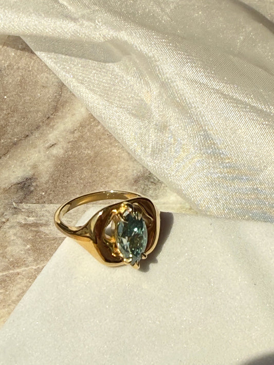 Gold ring with a green gemstone on a textured surface