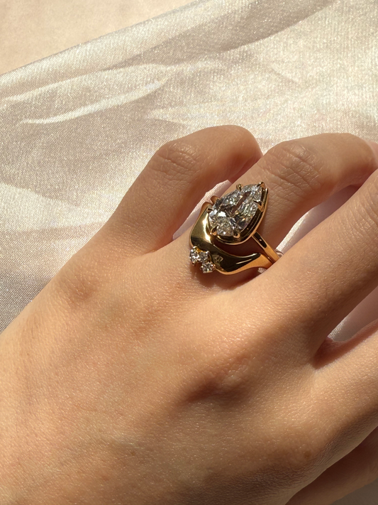 Gold ring with diamonds on a hand against a beige fabric background