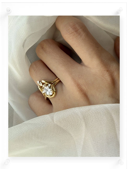 Gold ring with a diamond on a hand against a light fabric background