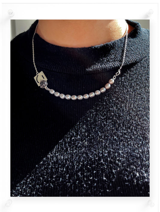Pearl necklace with a silver clasp worn by a person on a dark sweater.