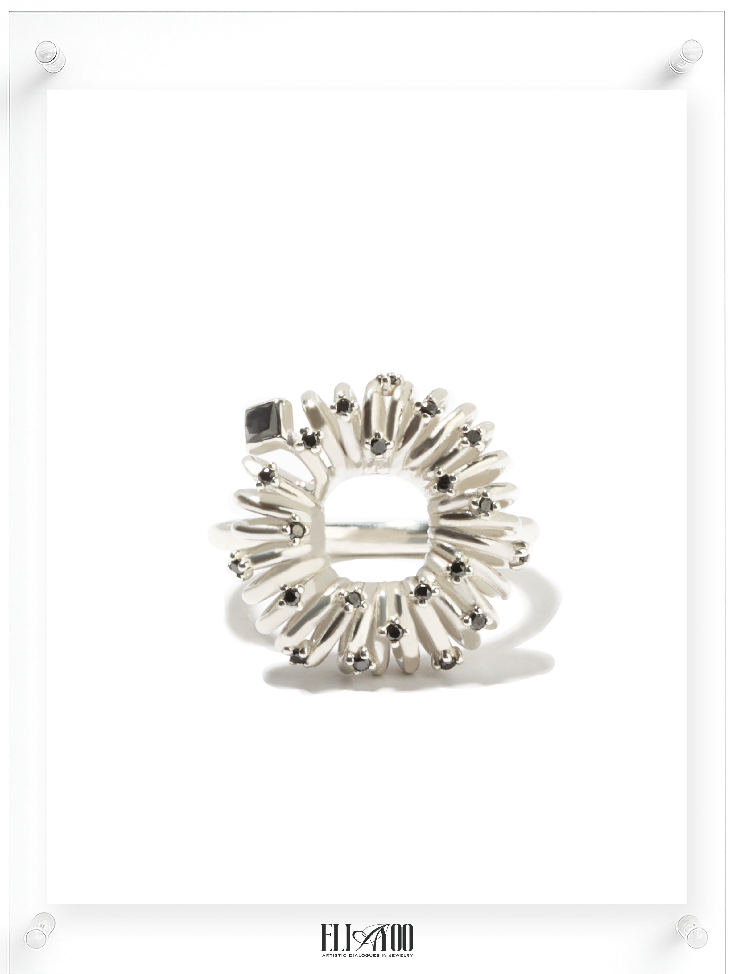 Front view of sculptural silver ring with circular petal setting and black diamond accents