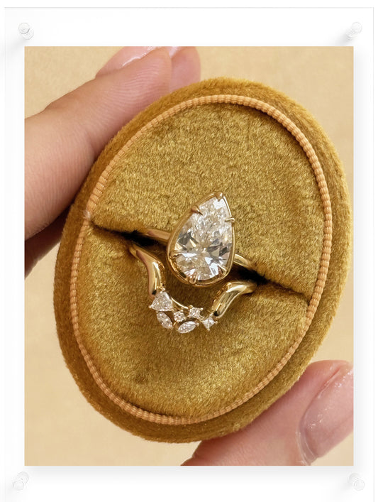 Gold ring with a diamond on a gold velvet ring box held by a hand.
