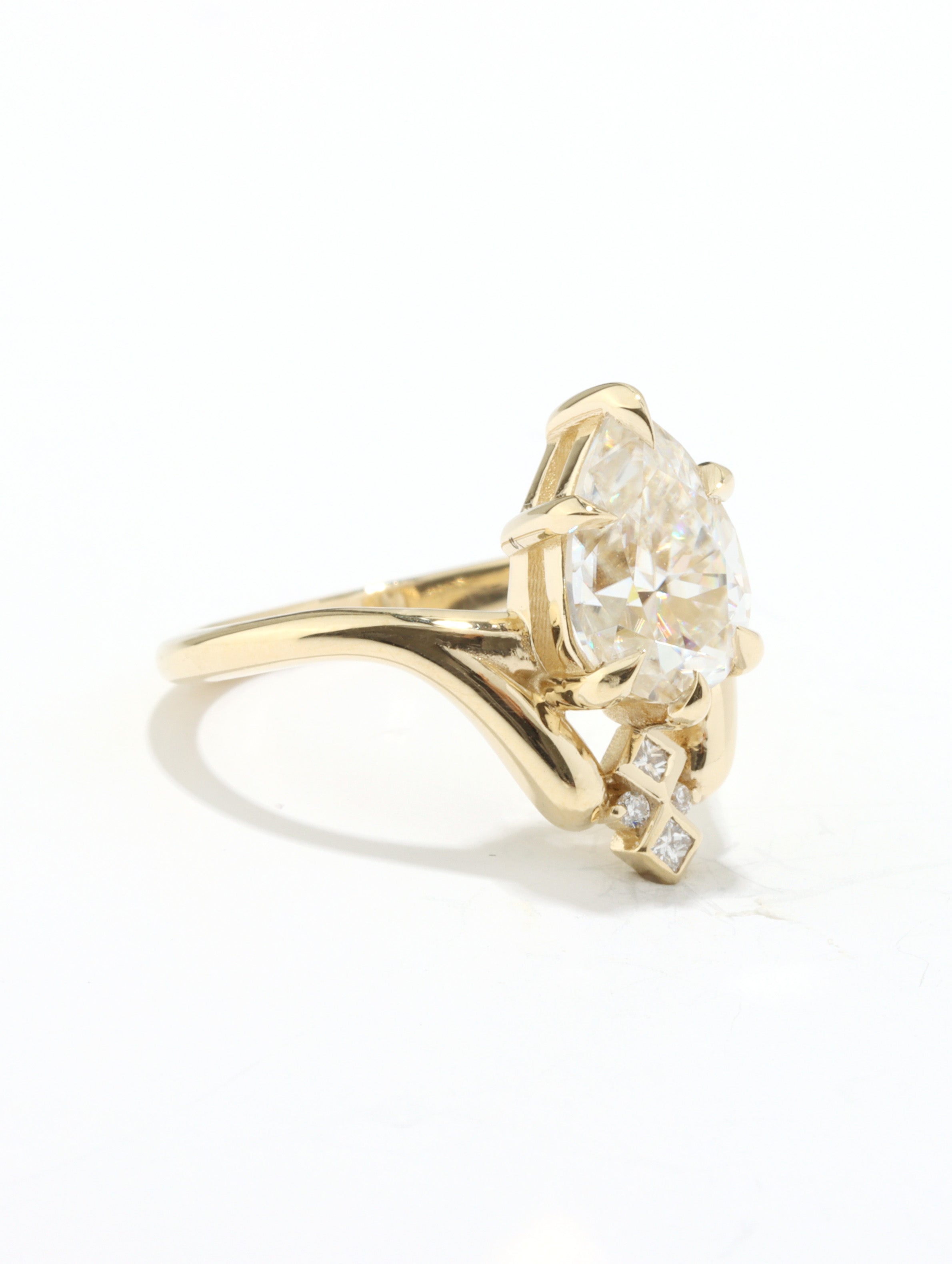 Gold ring with a large diamond and smaller diamonds on the band against a white background