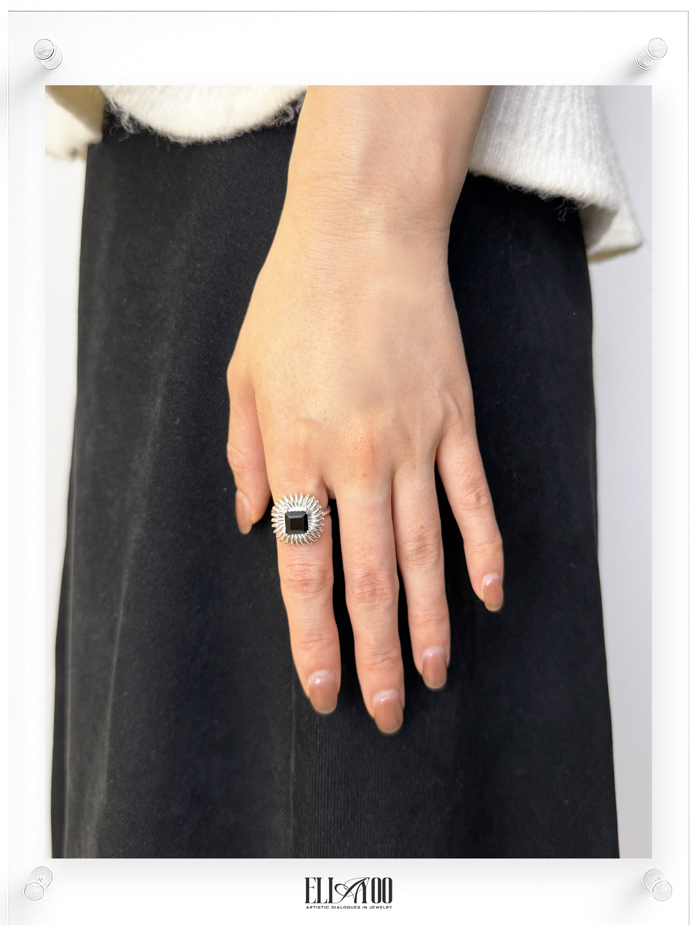 Princess cut onyx ring worn on model, sculptural silver petal setting