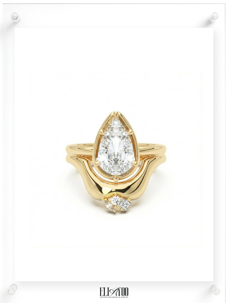 Yellow gold pear-shaped diamond ring with a sculptural flowing setting, soft natural light, front shot