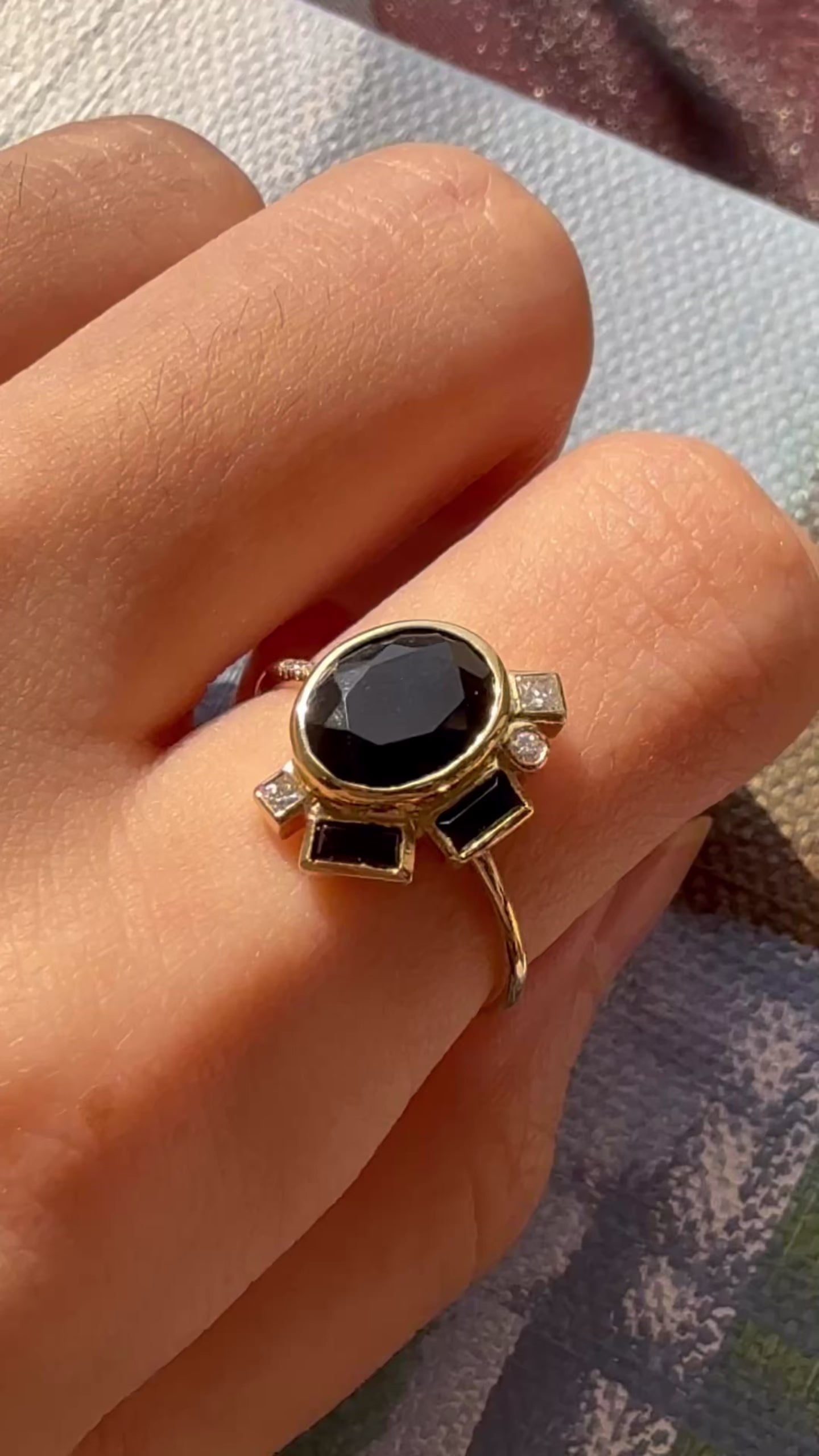 Video showing a 14K yellow gold ring with an oval black onyx and geometric stone accents worn on hand.