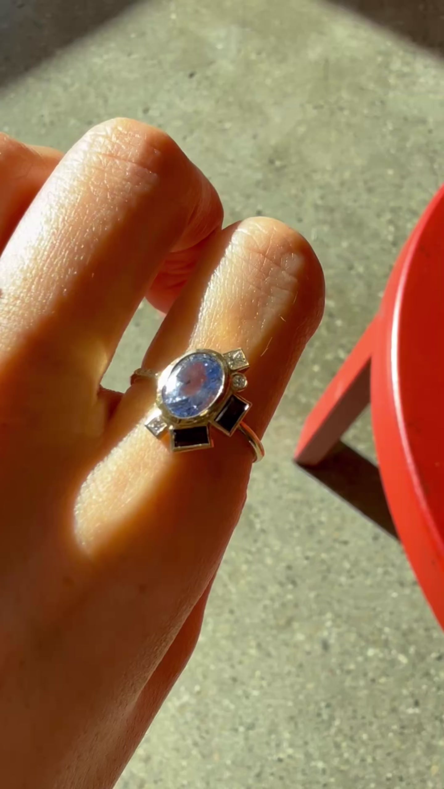 Video showing a 14K yellow gold ring with an oval blue sapphire and geometric sapphire accents worn on hand.
